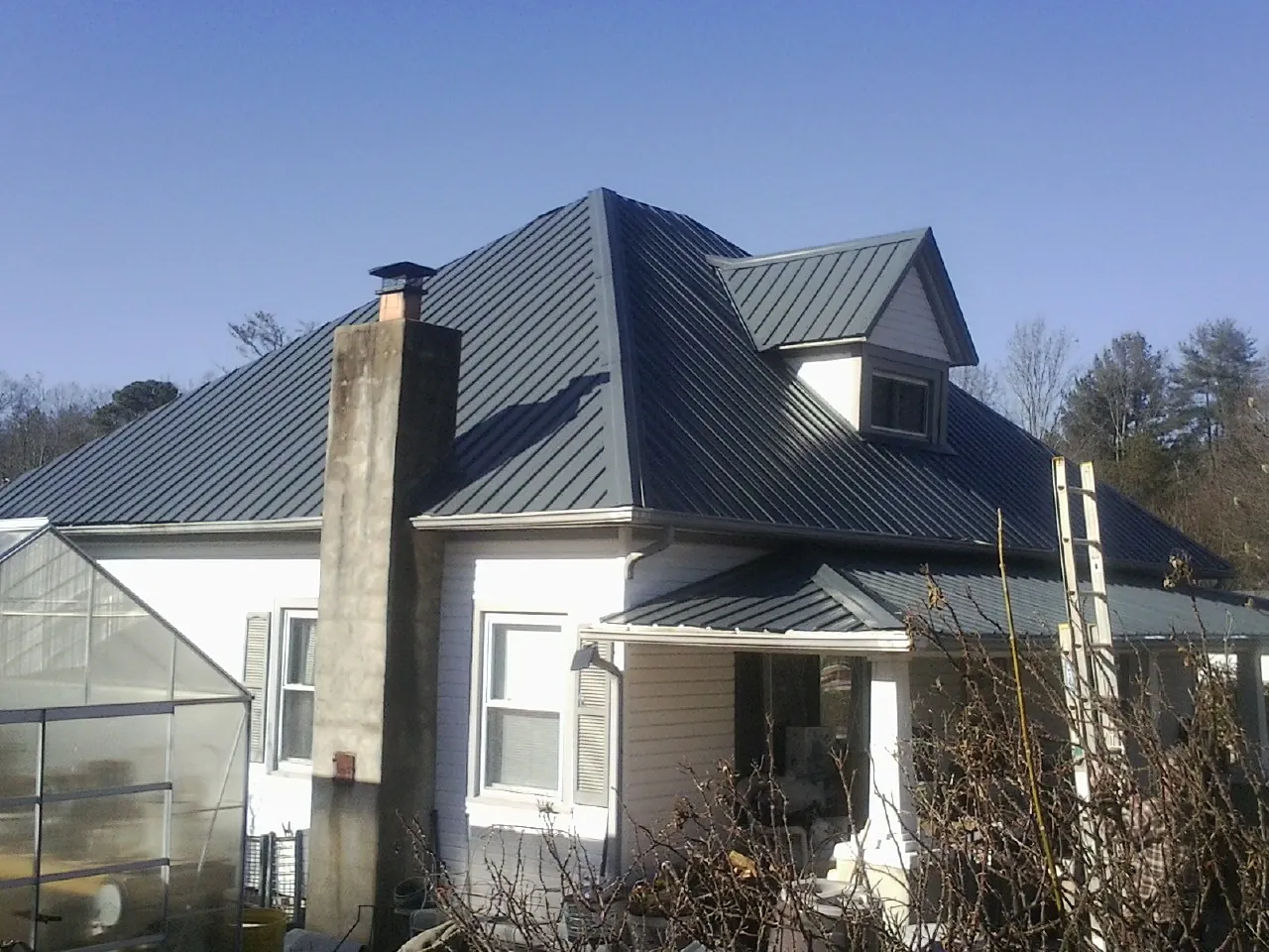 Dark blue standing seam metal roof on a white farmhouse with dormer — Slate & Tile Roof Repair by Roofing Brothers in Bentonia