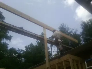 Carpenter setting a ridge beam over a new addition frame — Ice Dam Removal by Roofing Brothers in Bentonia