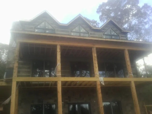 Dormers and porch framing on a large log home under construction — Roof Coating work by our crew in Bentonia