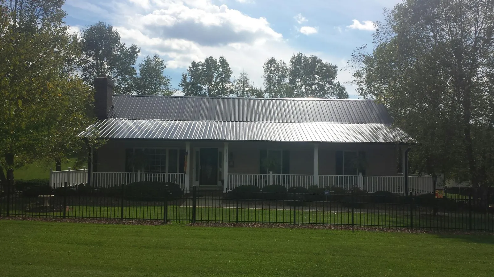 Gray metal roof on a brick ranch with a full width front porch — Gutter Guard Installation work by our crew in Bentonia